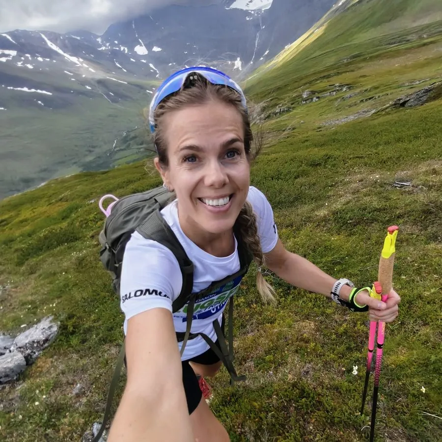 Anne Mjelva på fjelltur med staver, selfie i motbakke.