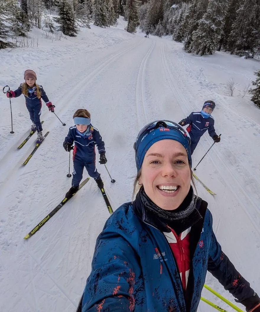 Anne Mjelva på ski i sporet med barna bak seg.